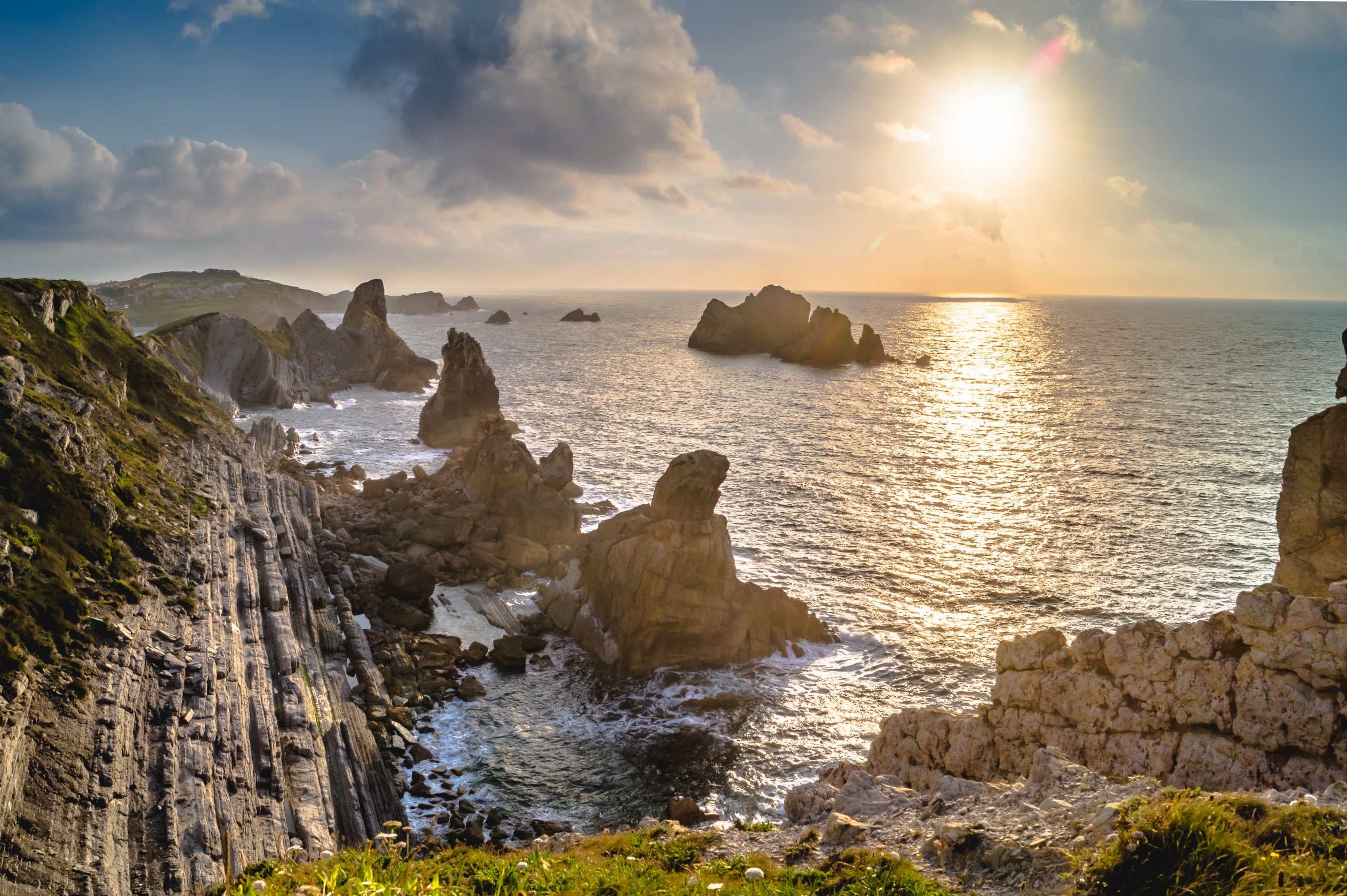 Sunset with sun, clouds and calm sea on cliffs of Costa Quebrada, Liencres, Spain